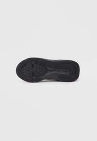 Semelle en caoutchouc de sneaker noire avec une construction texturée, comprenant des sections hexagonales et rainurées pour une meilleure adhérence.