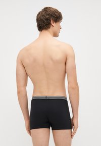 Melnas bokseris bikses, kas izgatavotas no mīksta, elastīga materiāla, ar joslu ar svītrām, sānu šuvēm un pieguļošu dizainu.