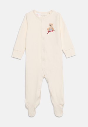 Roomkleurig babyrompertje met lange mouwen, drukknoopjes aan de voorkant en een kleine geborduurde teddybeer met de tekst "guess" op de borst.