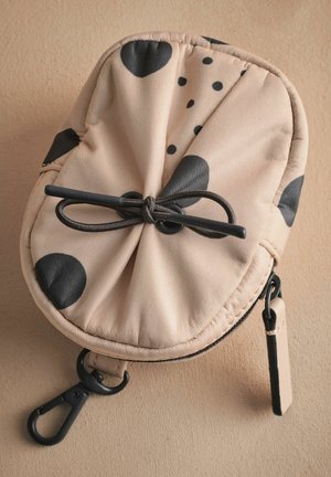 Beige Stoffbeutel mit großen schwarzen Punkten, gerafftem oberen Ende, verstellbarem Zugband und Metallverschluss. Glatte Textur, runde Form.