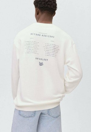 Sweatshirt en polaire crème avec une coupe décontractée. L'arrière présente un texte imprimé en bleu marine, listant des titres de chansons et le logo « Beyond Horizons ».