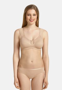 Soutien-gorge sans fil beige avec larges bretelles, texture lisse, détails de couture et fermoir central subtil, associé à un sous-vêtement hipster assorti.