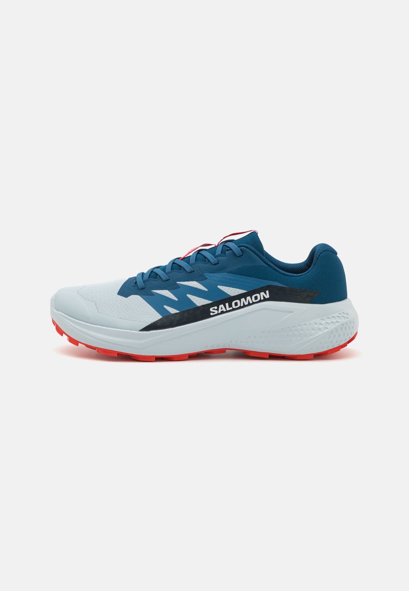 Running shoes with a light blue upper, black accents, and red outsole. Features textured material and prominent brand logo on the side.