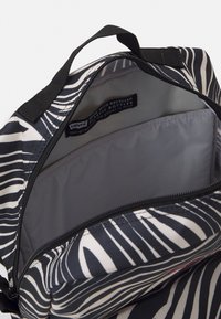 Ryggsäck i återvunnen tyg i svart och vitt med randigt mönster. Rymligt inre med grå foder och ficka med dragkedja. Hållbara remmar.