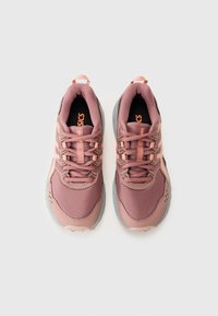 Baskets de sport rose clair avec tige en mesh, semelle grise contrastante et détails d'accent. Elles disposent d'un laçage traditionnel et d'un col rembourré.