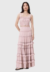 Vestido de dos piezas en rosa claro que presenta un top corto con fruncidos y tirantes con volantes, y una falda larga de capas con bordes con volantes y detalles de encaje.
