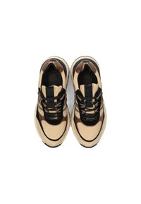 Sneakers beige e marroni con lacci neri, stoffa a rete e suole bianche spesse, viste dall'alto su uno sfondo bianco.