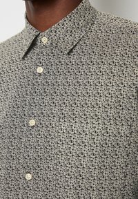 Korte mouw shirt met een zwarte achtergrond en een wit bladerenpatroon, met een button-down kraag en lichtgekleurde knopen.