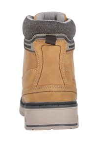 Brun läderboot med en grå vadderad krage, rund form och svart gummisula. Har kontrasterande sömmar och en dragflik bak för enkel påtagning.