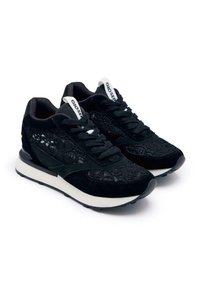 Zapatillas negras con un diseño de cordones texturizados y acentos de ante negro. Presentan suela blanca, cordones negros y una marca en la lengüeta.