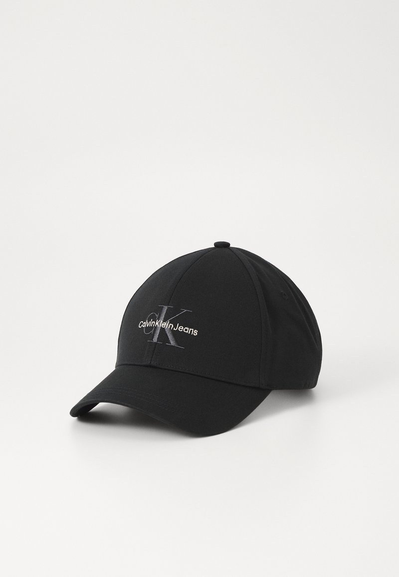 Fekete baseball sapka ívelt csúccsal, ezüst hímzett "Calvin Klein Jeans" logóval és fényes "K" betűvel az elején.