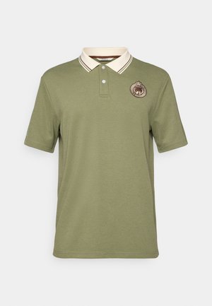Olivenfarget polo skjorte laget av bomull, med en hvit krage med brune striper og en rund logo-lapp på venstre bryst. Korte ermer.