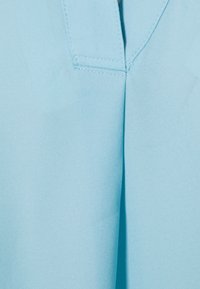 Hellblauer, glatter Stoff mit gefaltetem Design und sauberer Naht. Keine auffälligen Muster oder Beschläge sichtbar.