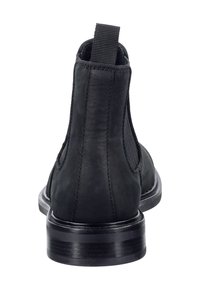 Černá kožená kotníková bota s elastickými bočními panely, zaoblenou špičkou a nízkým podpatkem. Obsahuje poutko na zadní straně pro snadné obouvání.