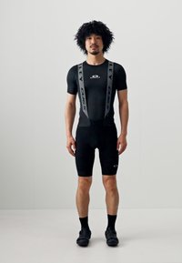 Costum de cycling negru cu mâneci scurte și pantaloni scurți, având bretele gri și accente cu logo. Textură netedă, design aderent.