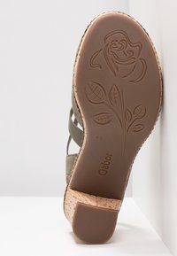 Vihreän viisteen sandaalin pohja, jossa on kohotettu kukkakuosi, Gabor-brändäyksellä, koko 4½, korkkikuvioitu kanta, esitettynä valkoista taustaa vasten.