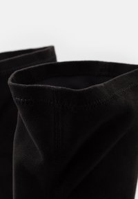 Botas de tobillo de ante negro con una textura suave, que presentan un borde superior doblado y sutiles detalles de costura, destacando su acabado liso.