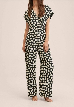 Sort jumpsuit med hvide polkaprikker, der har korte ærmer, omslagsfront, indsnøret talje og bukser med brede ben.