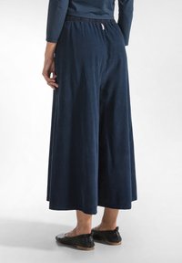 Marineblauwe wijde broek met een elastische tailleband en zachte textuur, met een relaxte pasvorm en een lengte tot de enkels.