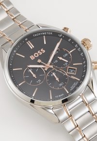 Orologio in acciaio inossidabile argento con quadrante nero, elementi in oro rosa, subquadranti cronografici e display della data. Impermeabile.