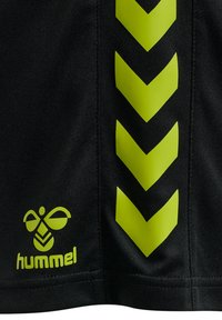 Pantalones cortos deportivos negros con prominentes patrones en forma de cheurón verde y logotipo. Fabricados con tejido suave, presentan un diseño moderno.