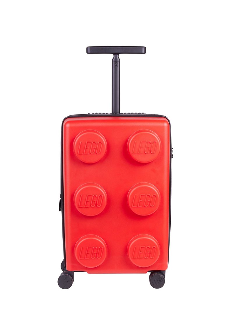 Red hard-shell suitcase with a textured, LEGO brick design, featuring six raised LEGO dots, a retractable handle, and four wheels.