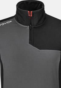 Halbzip-Pullover aus schwarzem und grauem Stoff. Verfügt über einen Stehkragen, ein kontrastierendes Schulterpaneel und eine kleine Reißverschlusstasche auf der Brust.