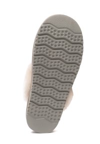 Gray rubber outsole with a wavy tread pattern and small dots, paired with a plush cream upper. Sturdy construction suitable for indoor use.