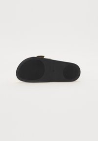 Black rubber sandal sole with a textured surface and smooth sections. Features a slight heel and no visible branding or patterns.