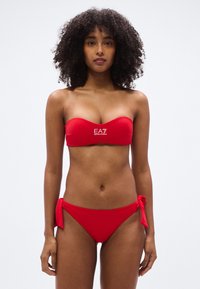 Σετ κόκκινου μπικίνι με τοπ μπαντό με λογότυπο και ρυθμιζόμενα κορδόνια στα πλευρά, κατασκευασμένο από λείο, ελαστικό ύφασμα.