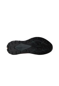 Suela de zapato deportivo negro con una textura de goma, que presenta tacos triangulares y una prominente cresta central para tracción y agarre.