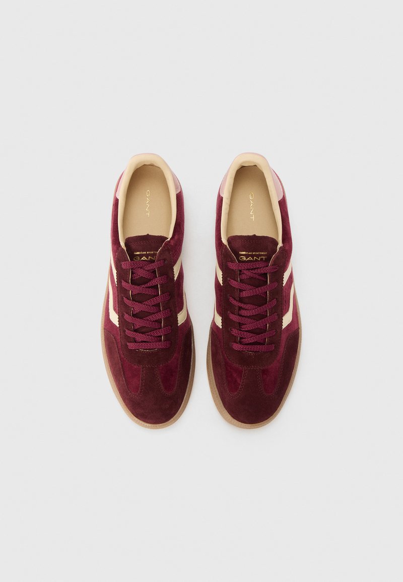Bordeaux-farbene Wildledersneaker mit cremefarbenen Streifen, strukturiertem Stoff und runden Schnürsenkeln. Beige Innensohlen mit goldenem Markenlogo innen.