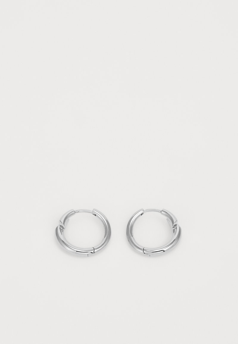 Brincos em argola prateada com um acabamento liso e polido. Forma circular com um pequeno detalhe de fecho. Design minimalista, leve.