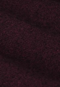 Tissu bordeaux avec un tissage texturé, affichant une surface douce, légèrement veloutée et une couleur riche et profonde.