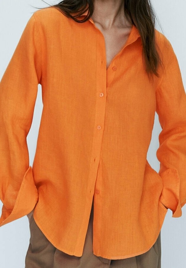 Orangenes Leinenhemd mit Knöpfen, Stehkragen, langen Ärmeln und weiter Passform. Verfügt über Frontknöpfe und hochgekrempelte Ärmelbündchen.