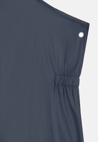 Casaco leve azul marinho com cintura elástica, textura suave, detalhe de botão de pressão e um design elegante e minimalista.