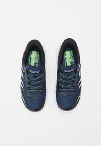 Baskets de sport marine et noires avec tige en mesh, accents verts et semelle blanche. Comprend des lacets et un logo sur la languette.