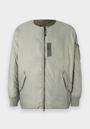 Giacca bomber verde chiaro con zip frontale, due tasche laterali, polsini a coste e una patch sul petto. Finitura liscia e opaca.