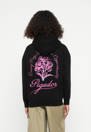 Schwarzer Kapuzenpullover mit einer Fronttasche. Der Rücken zeigt ein großes, pinkfarbenes Blumenmotiv mit dem Text "Jeder Tag ist eine neue Gelegenheit" und "Pegador."