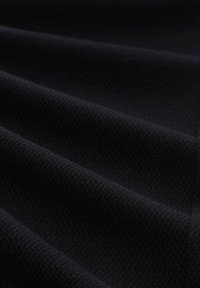 Zwart, textielstof met een subtiel visgraatpatroon. Het materiaal lijkt zacht en flexibel, gerangschikt in zachte plooien.