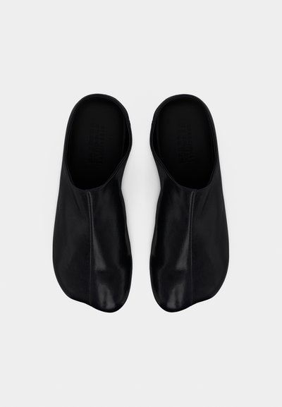 Μαύρα δερμάτινα παπούτσια χωρίς κορδόνια με λεία, γυαλιστερή επιφάνεια, με μινιμαλιστικό σχέδιο και στρογγυλεμένη μύτη. Χωρίς εμφανή εξαρτήματα ή διακοσμητικά στοιχεία.