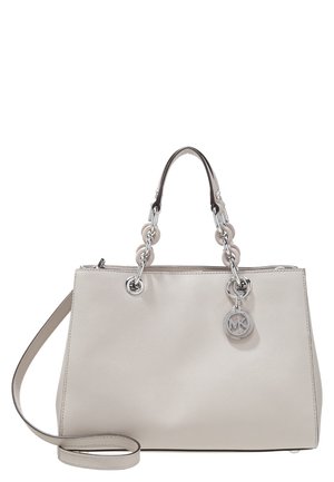 Sac à main en cuir crème avec des poignées en chaîne argentée et un pendentif logo MK argenté, avec une bandoulière amovible.