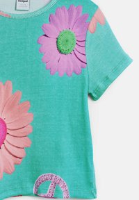 Tričko s krátkymi rukávmi v odtieni teal, vyrobené z textúrovaného rebrovaného materiálu, s veľkými potlačami ružových a fialových kvetov a detailom symbolu pokoja.