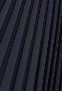 Tissu navy plissé avec des plis verticaux, présentant une texture lisse. Conçu avec des creux profonds et réguliers pour un tombé structuré.