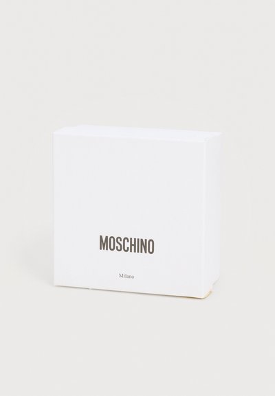 Λευκό ορθογώνιο κουτί με την επωνυμία Moschino Milano, σε απλό ανοιχτόχρωμο φόντο, ορατό ελαφρώς από το πλάι.