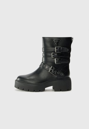 Svarte lær ankle boots med tre spente stropper, teksturerte detaljer, tykk gummisåle og en triangel-logo på forsiden.