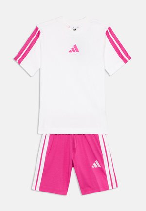 Camiseta deportiva blanca con rayas rosas en las mangas y un pequeño logo rosa. Pantalones cortos rosas con rayas blancas en los laterales y un logo a juego. Mezcla de algodón.