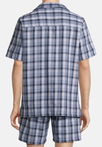 Ensemble composé d'une chemise à manches courtes et d'un short, avec un motif écossais bleu, noir et blanc, offrant une coupe décontractée et une texture de tissu lisse.