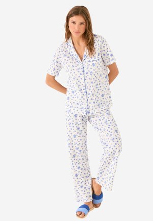 White cotton pajama set featuring blue floral pattern, short-sleeved top with pocket, and matching flared pants; paired with blue slide sandals.