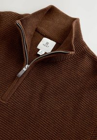 Brauner Pullover mit Reißverschluss aus strukturiertem Stoff, mit einem gerippten Kragen. Das Etikett zeigt die Marke "NEXT" und die Größe "M".